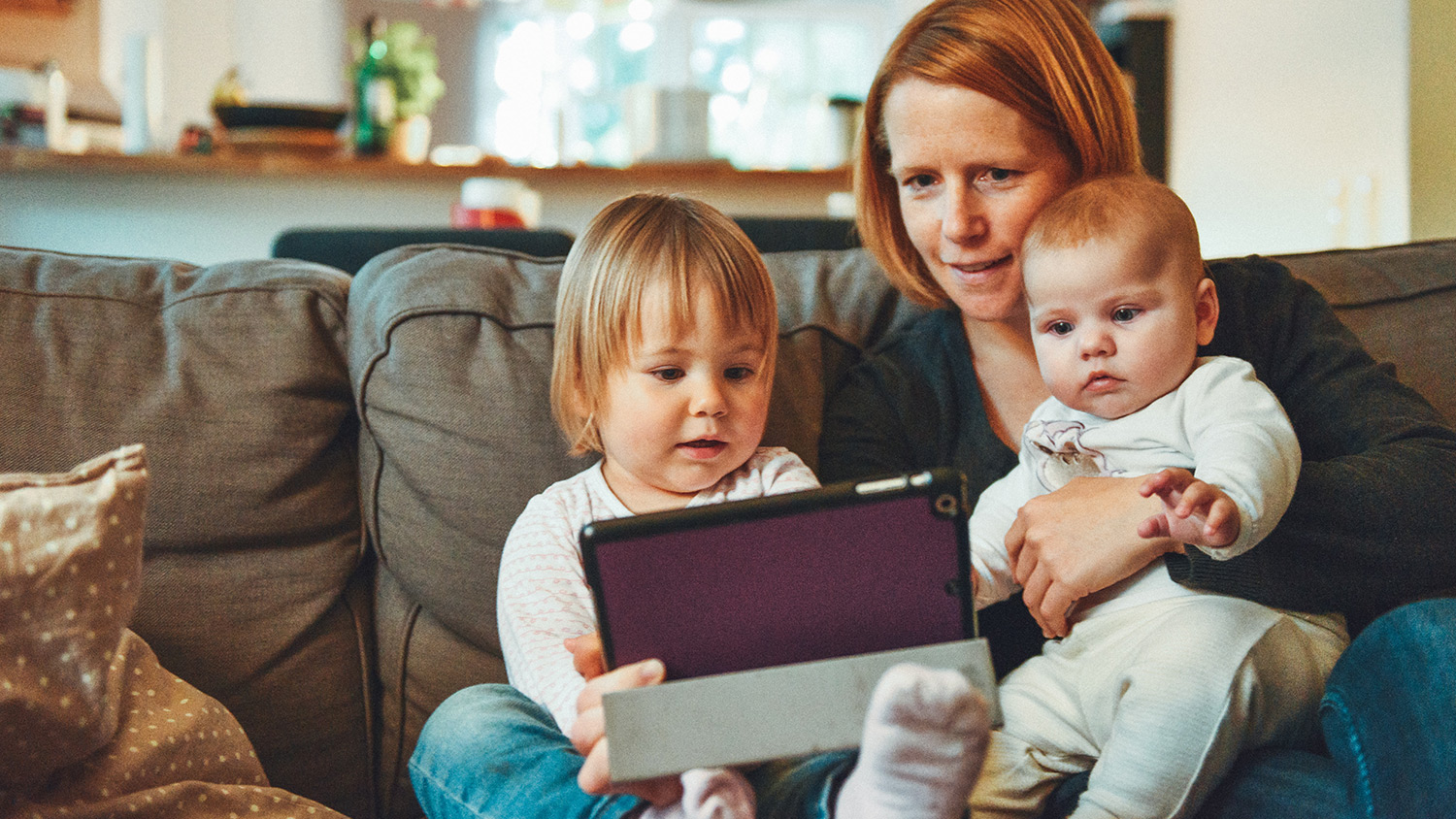 Woman holding two children and iPad