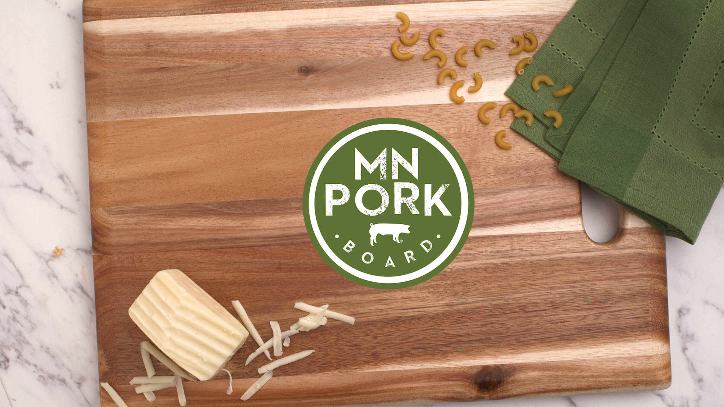 Minnesota Pork Board campaign image with branded cutting board, cheese and pasta