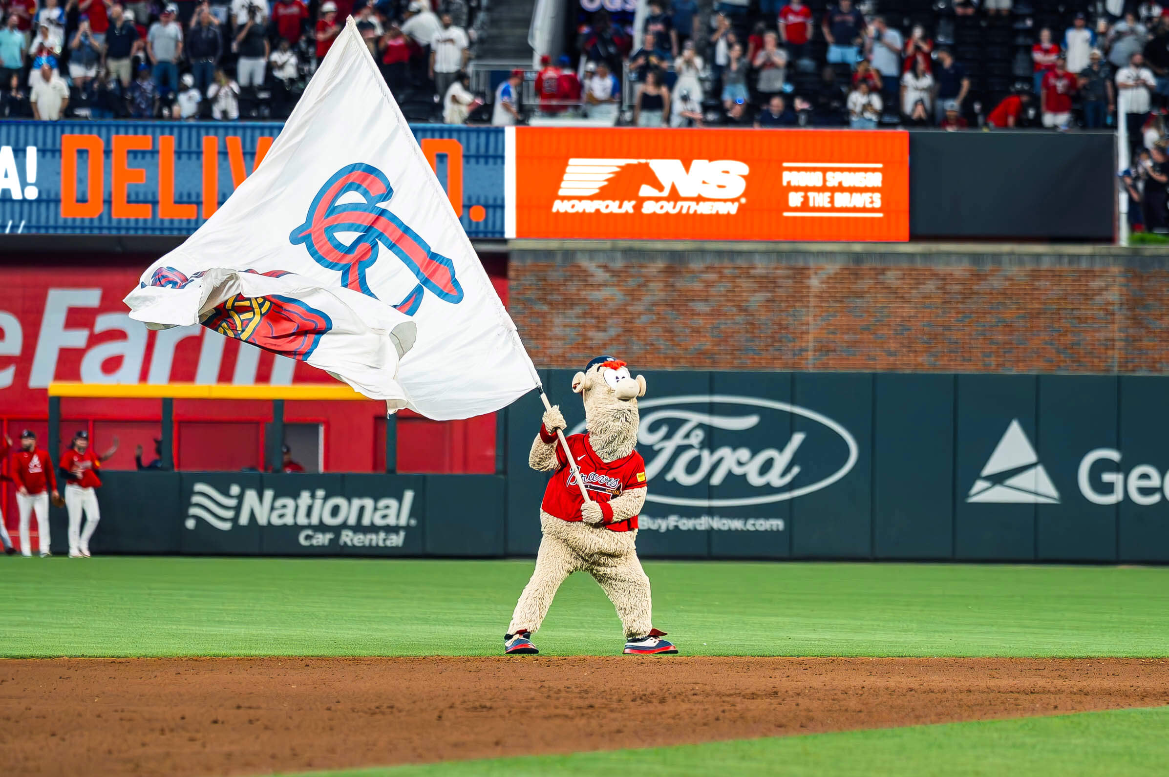 Atlanta Braves mascot waving flag with Norfolk Southern digital banner in the background.